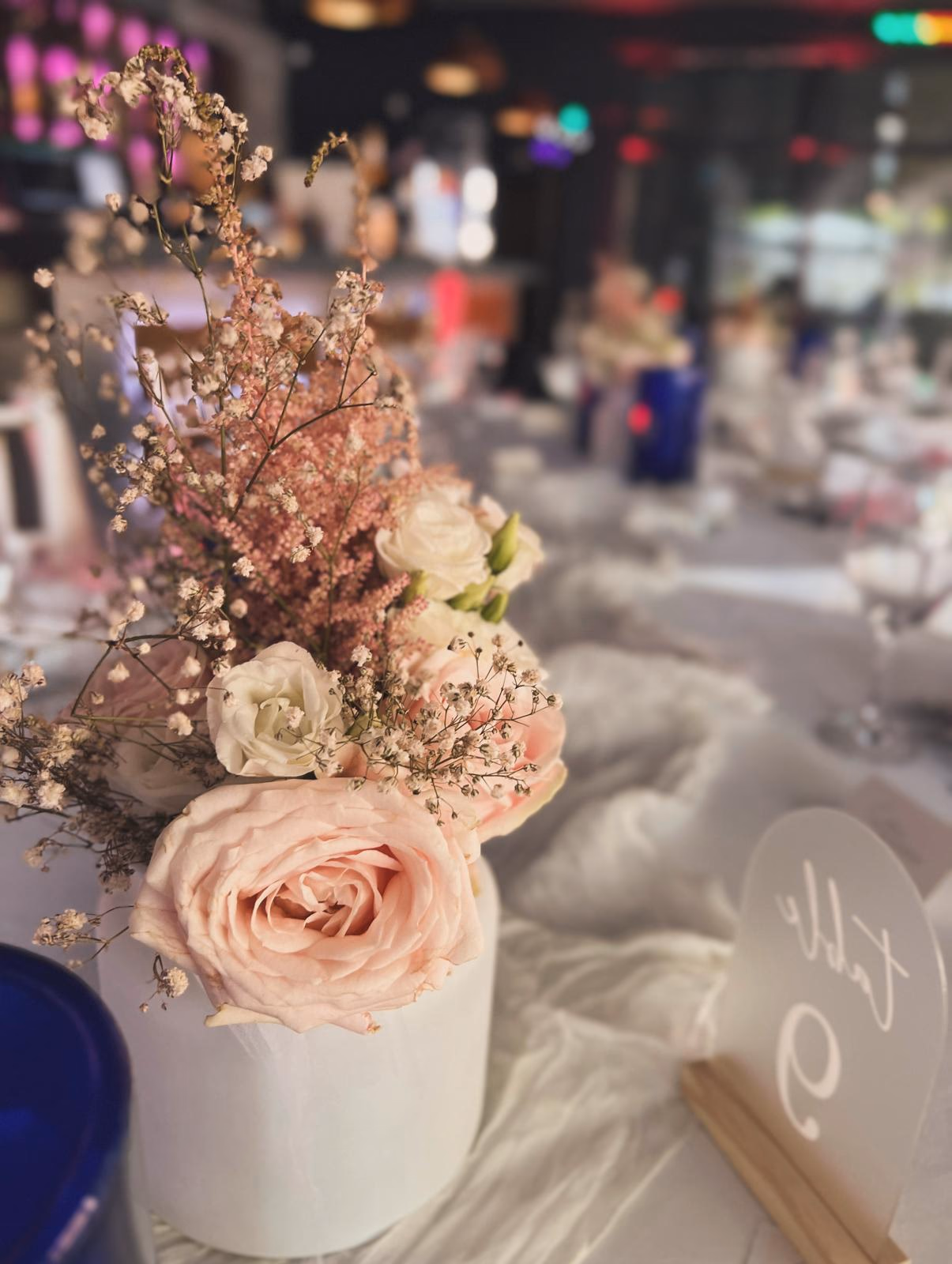Rosa Rosen, Astilbe und Schleierkraut in mattem Keramikzylinder, sanfter Bokeh-Hintergrund.